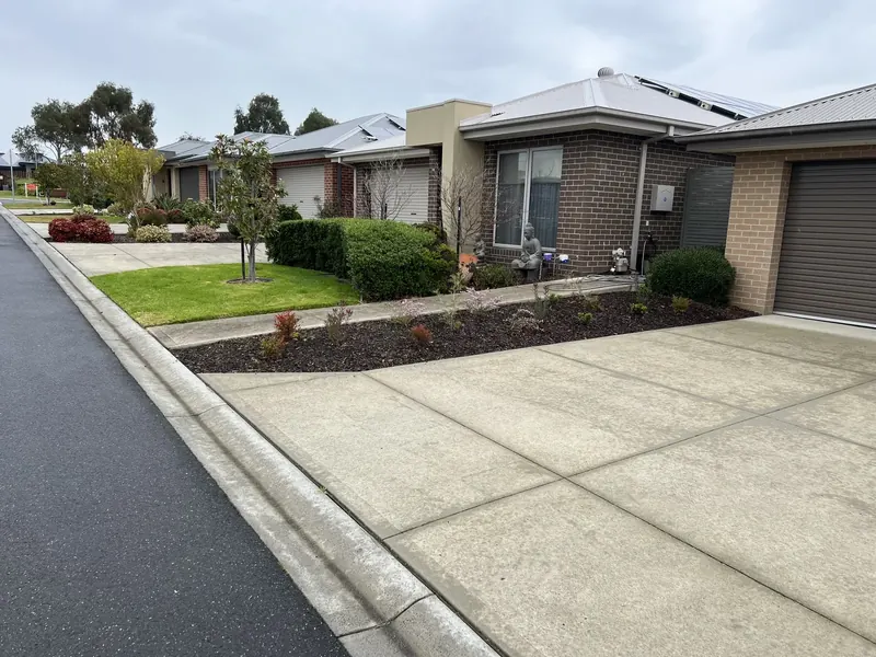 Mown common-area lawn and clipped garden beds at a body corporate complex in Clyde North