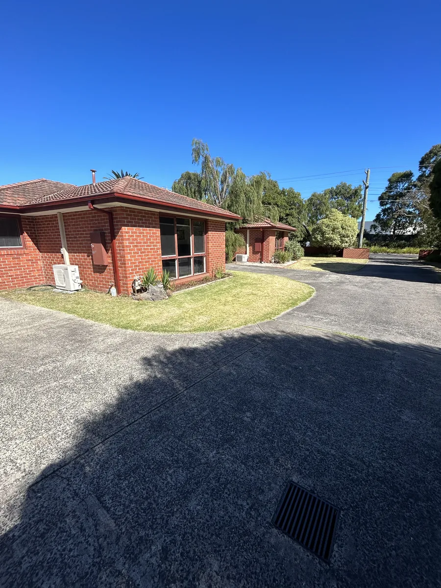 Common area garden beds and lawn maintained beside a resident path in Frankston