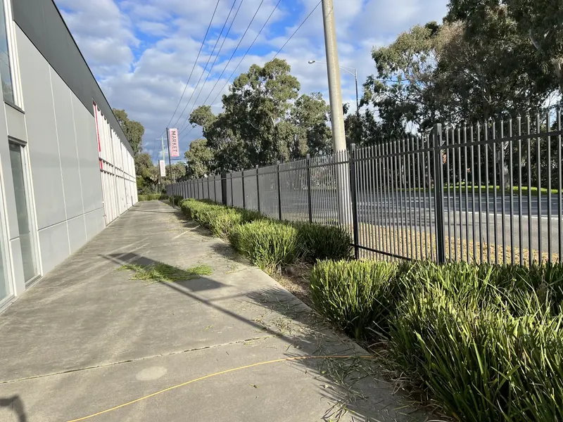 Cut grass and a clear fenceline along the boundary of an industrial site